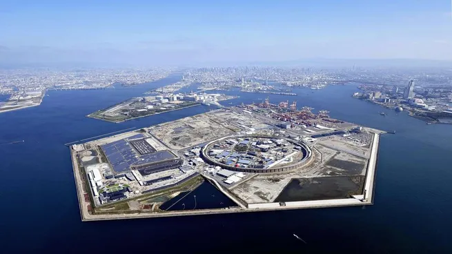 Vista aérea de la isla artificial Yumeshima en la bahía de Osaka, sede de la Expo Osaka 2025, con el Gran Anillo de madera y pabellones internacionales rodeados por el mar.