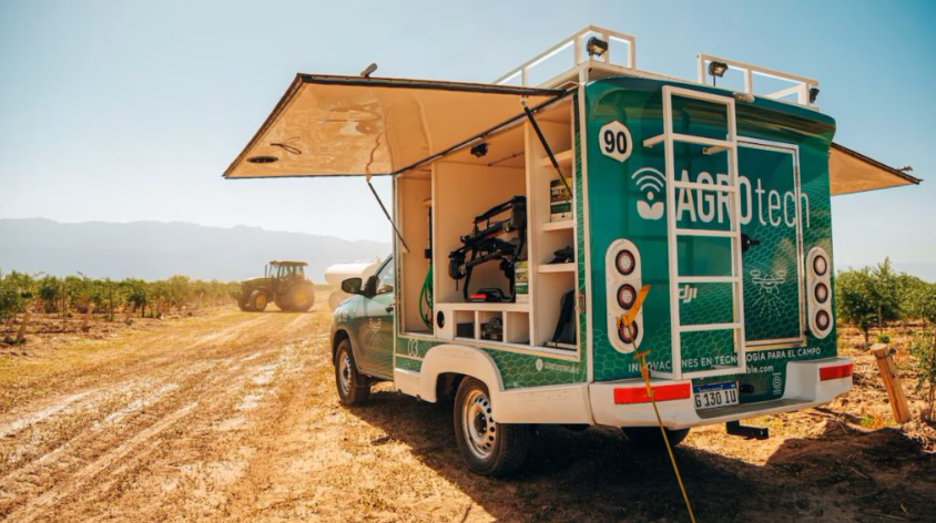 Unidad móvil de AgTech equipada con drones y tecnología agrícola operando en un cultivo para monitoreo y aplicación de bioinsumos en campo.